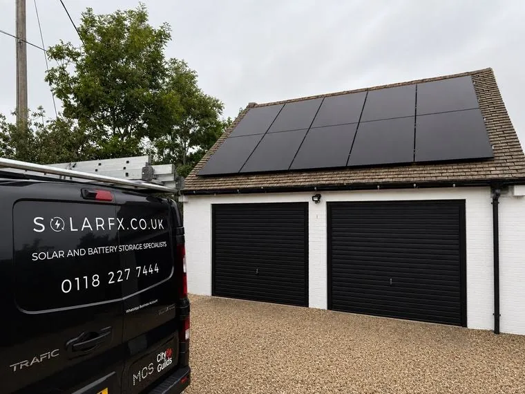 Ten black solar panels on a garage roof with a SolarFX van on the drive