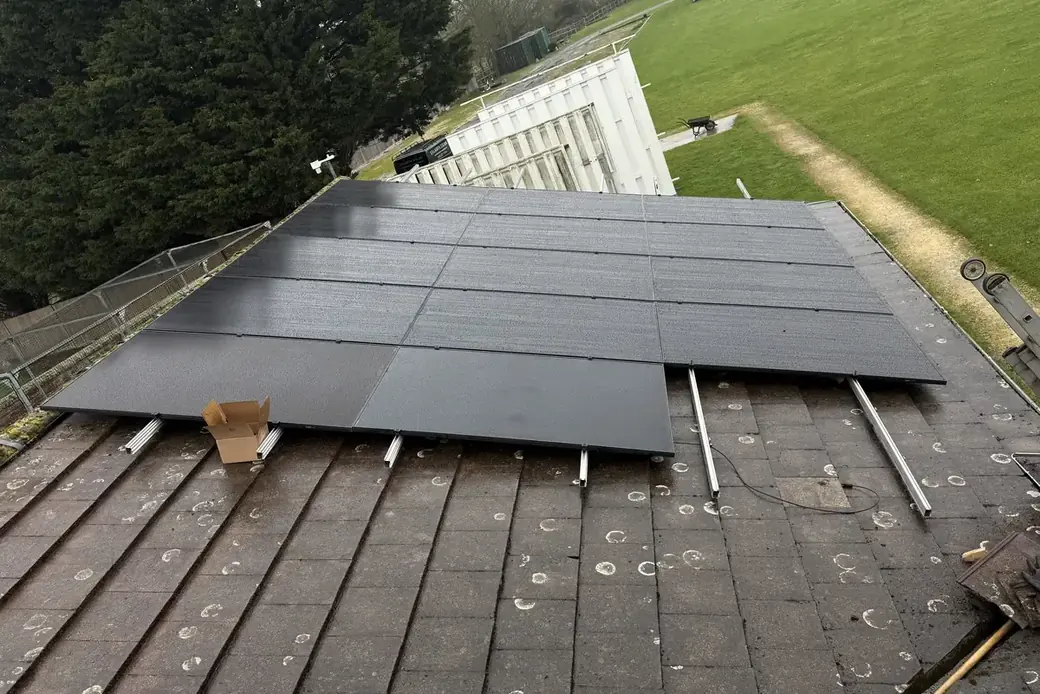 Black solar panels being laid out across a roof during installation
