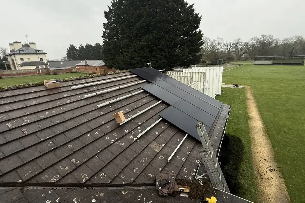 Mounting rails and fixings across a roof with the first panels in place