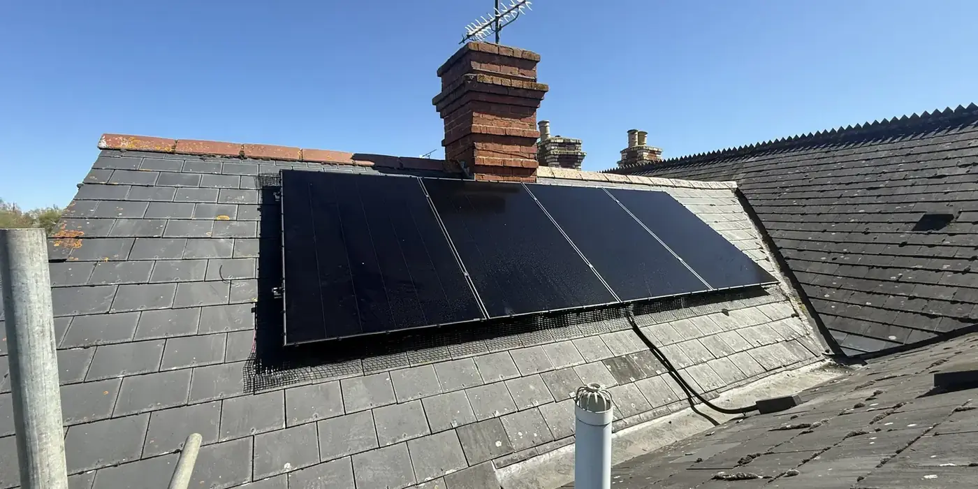 Solar array fitted on a slate roof beside a brick chimney