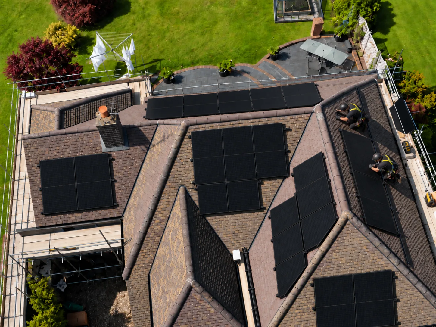 SolarFX installers fitting black solar panels across a tiled roof, seen from above